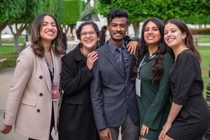 A group of diverse colleagues smiling together, showcasing teamwork and friendship outdoors.